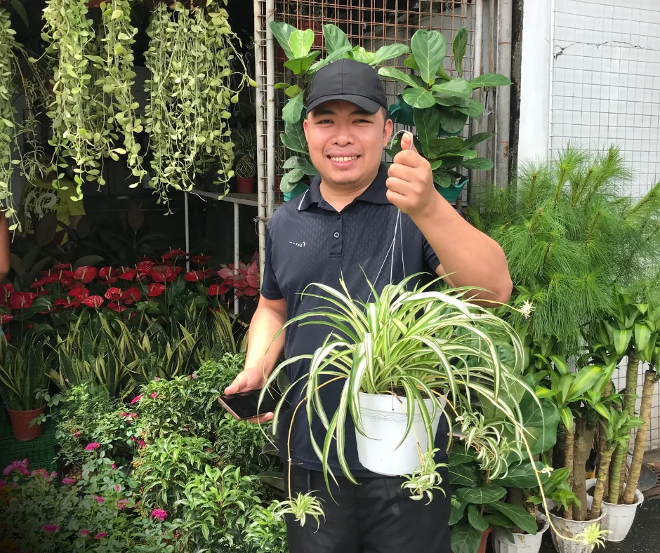 Joemar Villalobos holding a spider plant at an Urban Goes Green garden center in Metro Manila